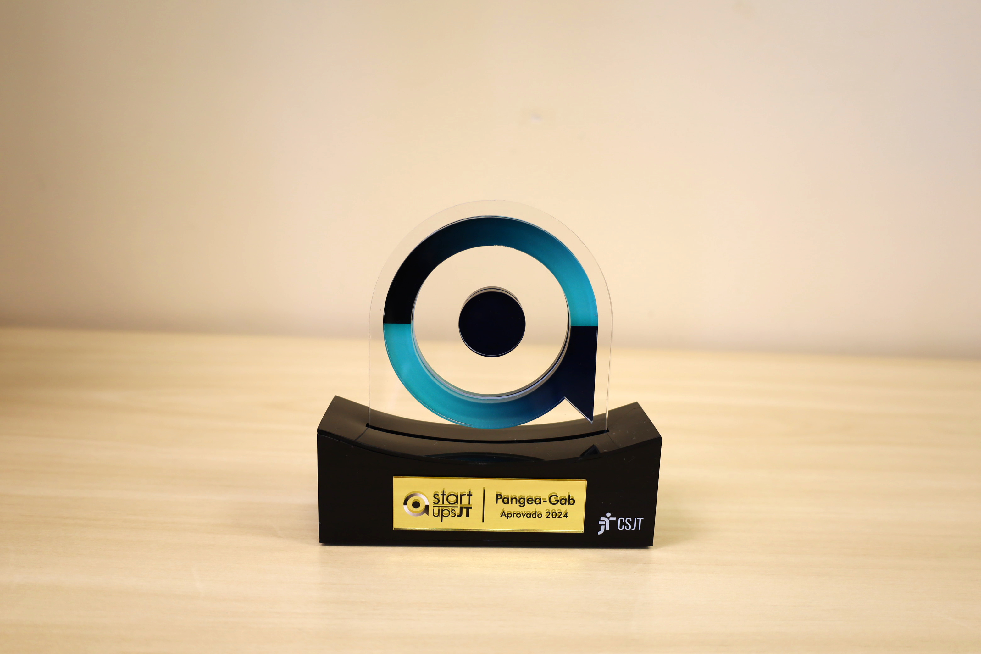 foto de troféu em acrilíco com logo em formato circular e círculo menor dentro, em base preta