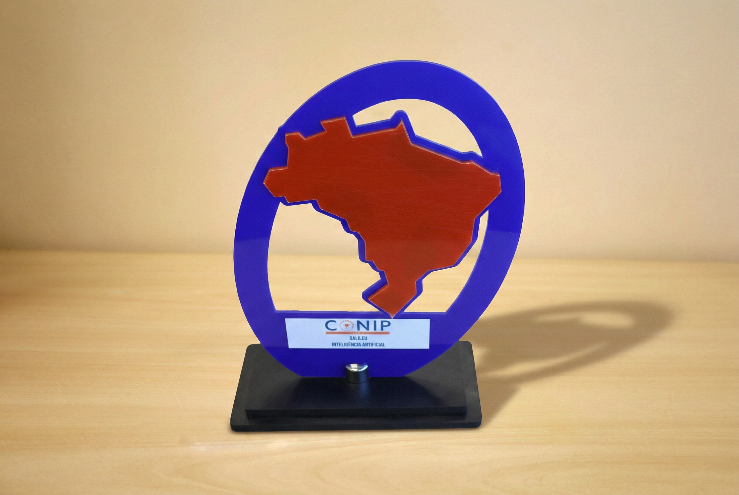 foto de troféu do mapa do rio grande do sul em vermelho circulado em azul numa base preta