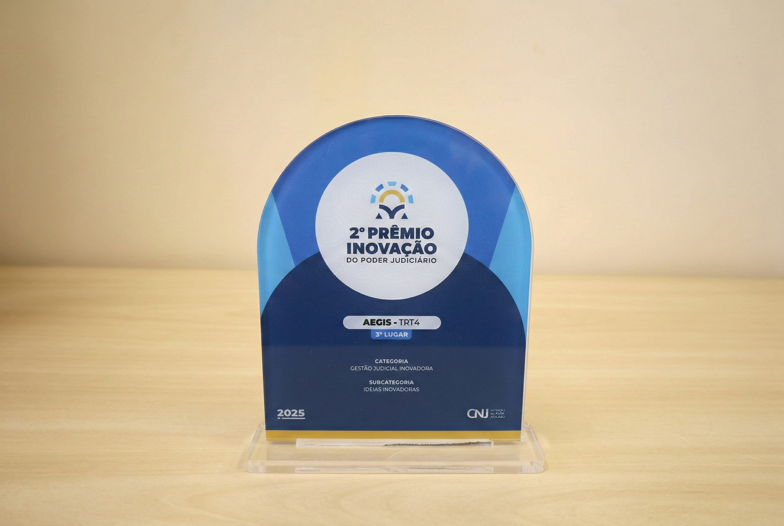 foto de troféu em acrílico em formato de retângulo com topo semicircular em tons azuis com o título do evento no meio